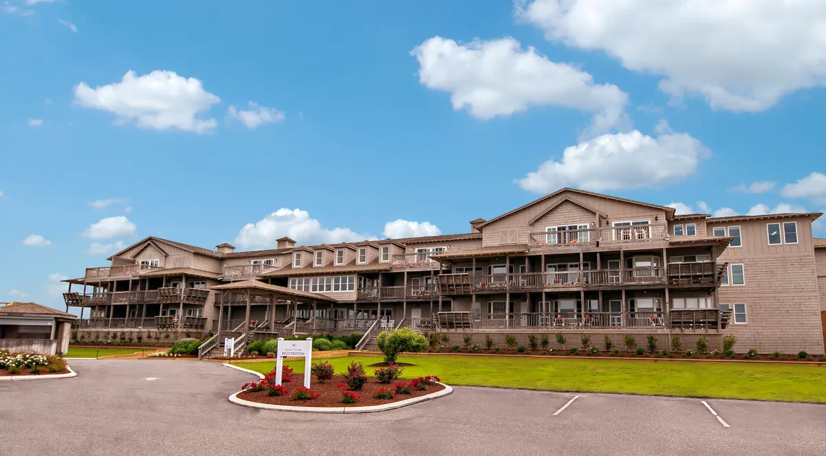 A welcoming exterior featuring a spacious front porch and multiple balconies overlooking a landscaped garden. The scene hints at a tranquil, private outdoor environment designed for relaxation, with ample seating and open views that capture the essence of oceanfront serenity.